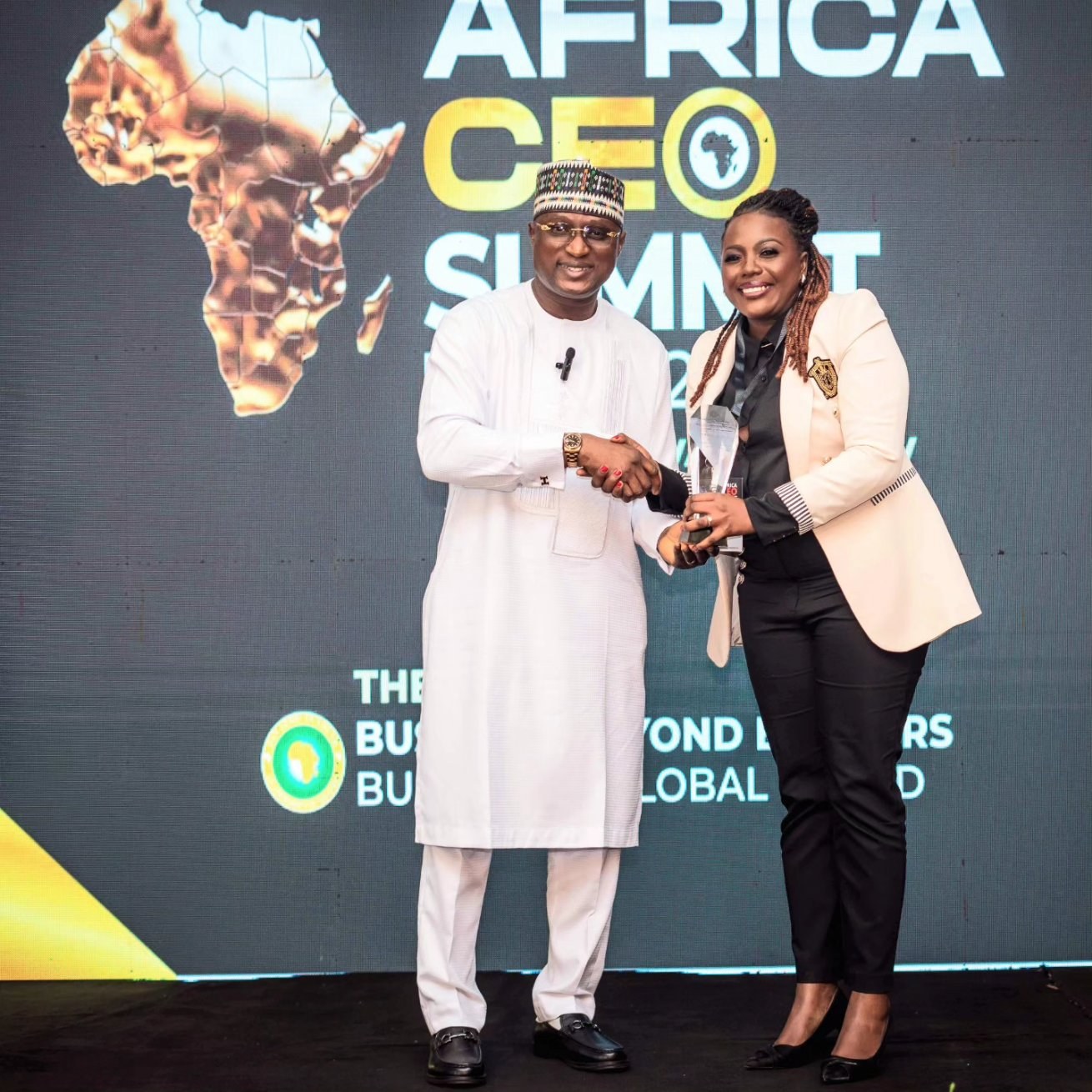 Two people presenting an award at the Africa CEO Summit, with their faces, handshake and trophy visible.