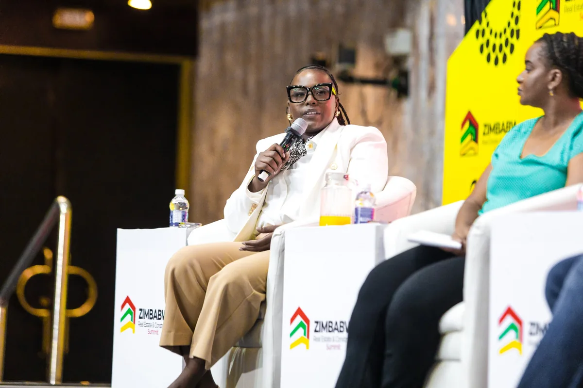 Seated speaker holding a microphone during an industry panel discussion.